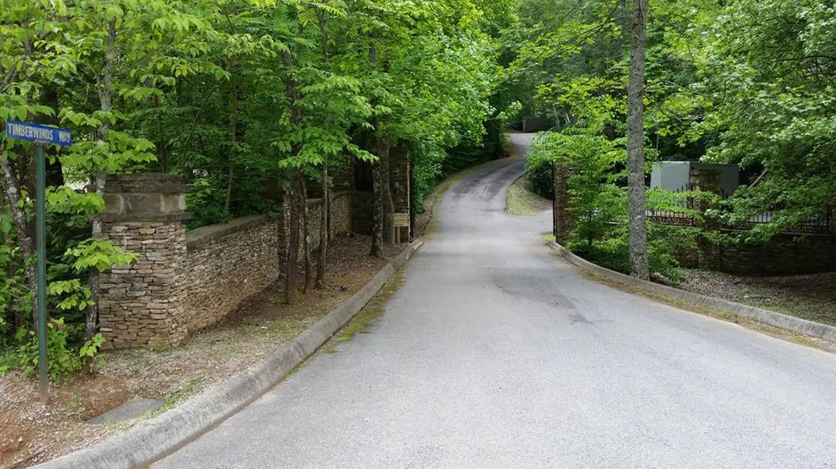 A winding road lined with stone walls and surrounded by lush greenery leads through the Smoky Mountains, inviting exploration and discovery. The tranquil scene suggests opportunities for walking, scenic drives, and enjoying peaceful moments in nature.